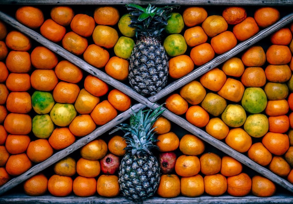 Wooden crate with pineapples and oranges inside
