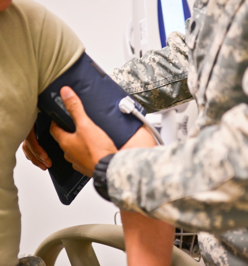 A military health care provider putting a blood pressure cuff around a GI's arm.