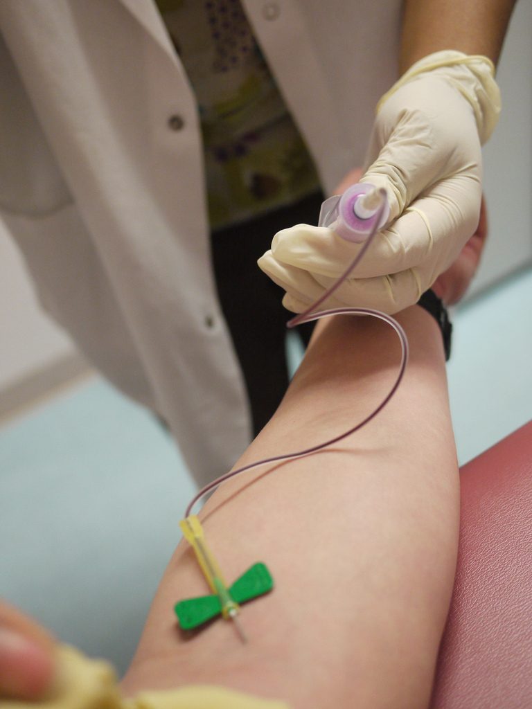 Photograph of a healthcare provider drawing blood from a patient's arm.